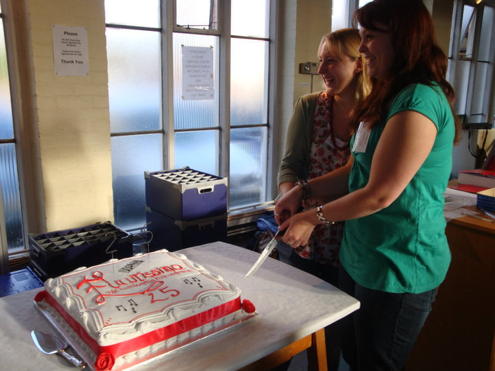 Current musical directors Harriet Rudge and Kate Roberts cutting the cake